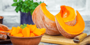 Ciotola di cubetti di zucca fresca accanto a una zucca tagliata a spicchi, pronta per cucinare ricette con la zucca sane e gustose, ideali per piatti autunnali colorati e nutrienti.